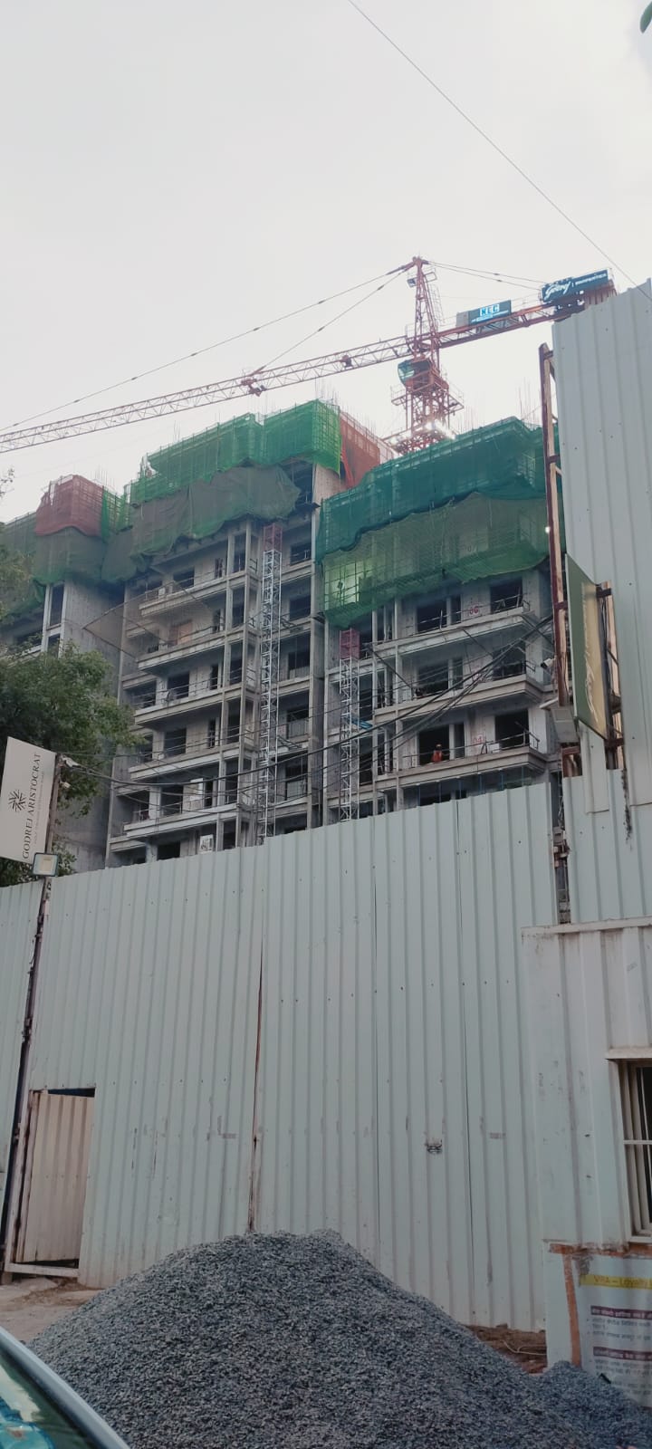 Multi-storey building under construction in Gurgaon Sector 49, with a tower crane and green safety netting